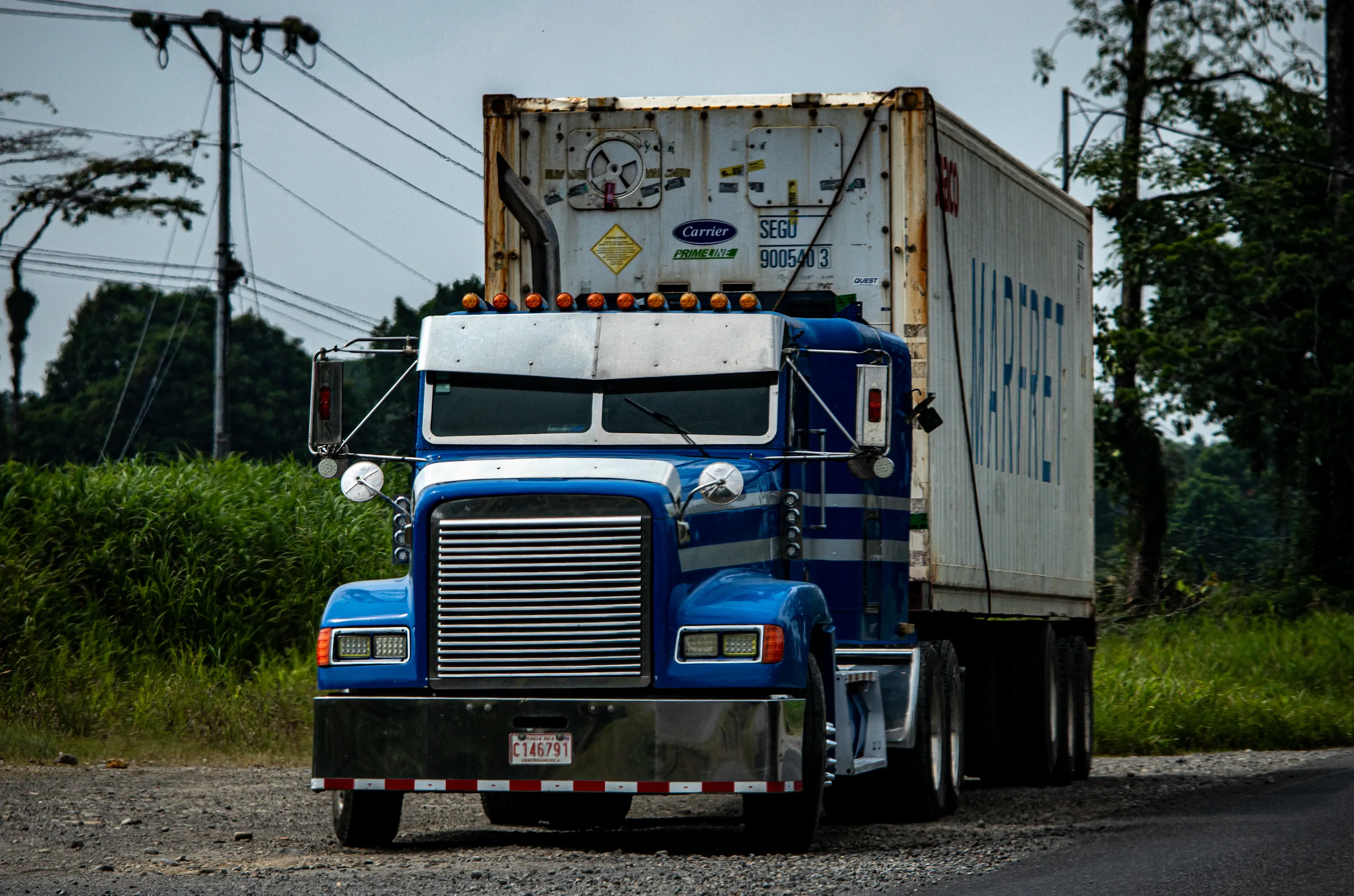 Blue Freightliner tractor pulling a shipping container